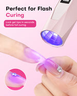 Hand using a Gugusure pink mini UV LED nail wand to precision cure and lock a purple gel tip in place.