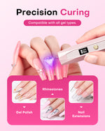 Hand holding a Gugusure pink wand nail light to precision cure rhinestones on a long pink gel nail extension.