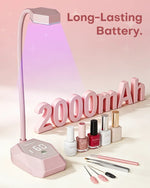 Pink cordless nail lamp showcasing its 2000mAh long-lasting battery, surrounded by gel polish and manicure tools.