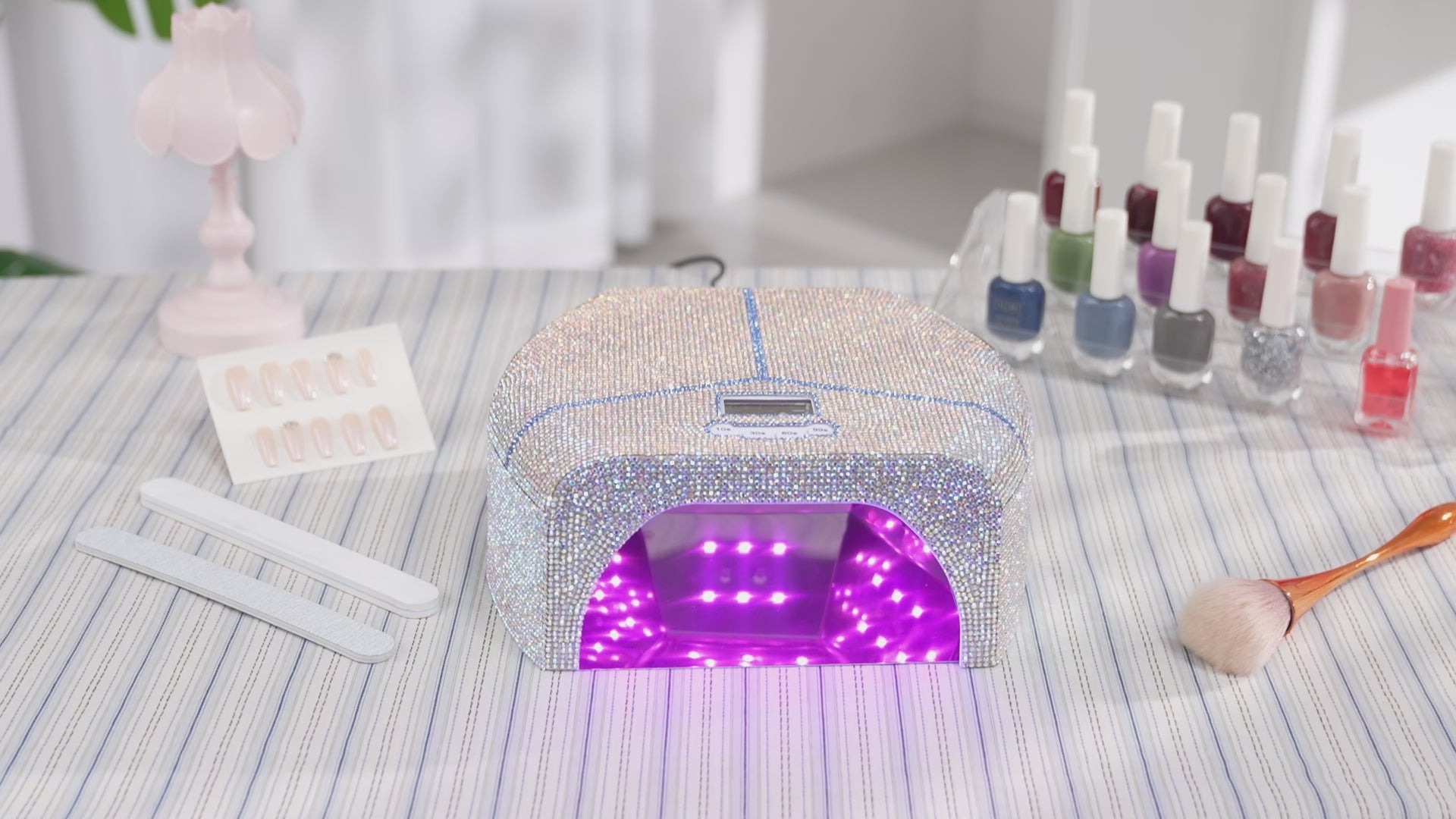 Gugusure luxury rhinestone UV LED nail lamp turned on, displayed on a home salon table with gel polishes and manicure tools.