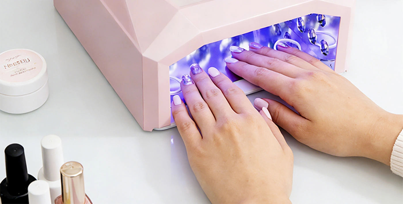Woman placing both hands inside the spacious pink aluminum gel nail drying lamp. The reflective metal interior and strategically placed LEDs ensure a flawless, even cure in seconds without smudging.